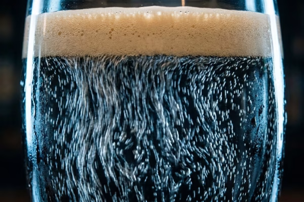 Close-up of nitrogen bubbles cascading downward inside a glass of Irish dry stout, creating the iconic surge and settle effect