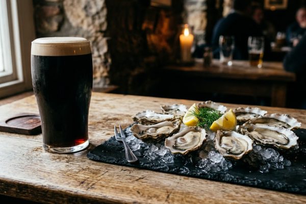 A pint of Irish dry stout beside a platter of fresh oysters on ice, the classic Irish beer and seafood pairing